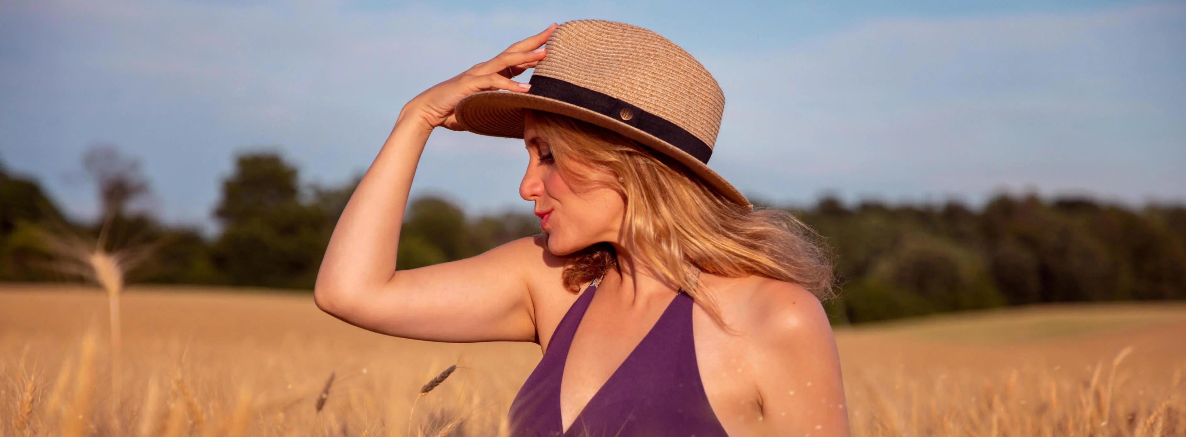 Woman wearing a straw hat and purple top in a field